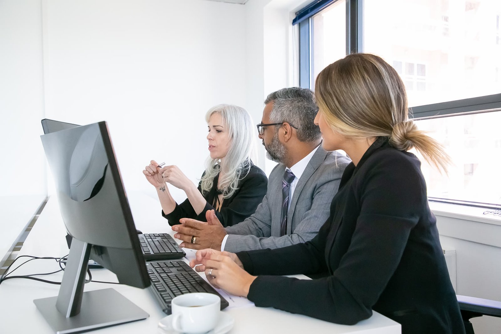 Profissionais de tecnologia discutindo um projeto diante de monitores